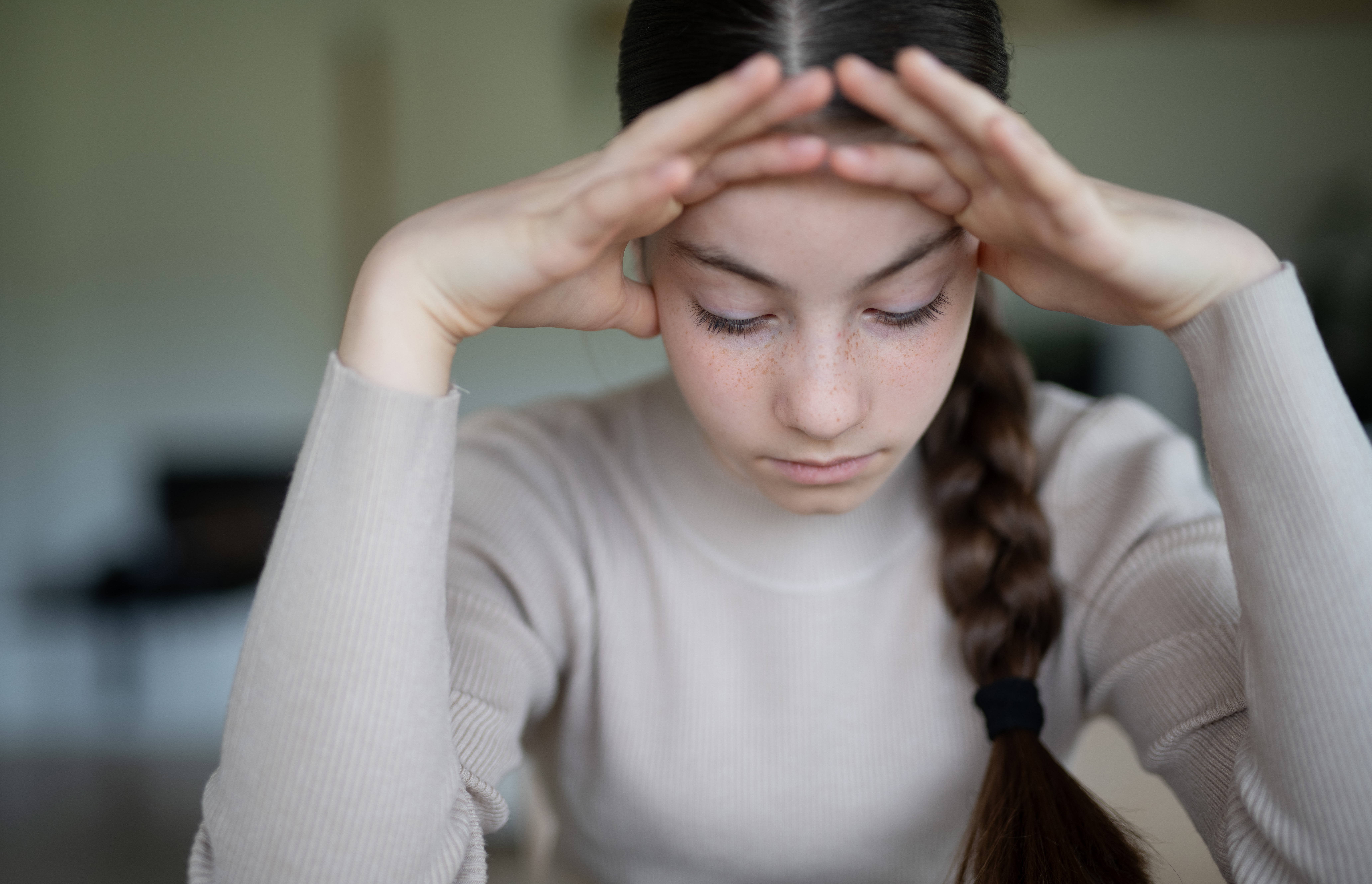 Junge Frau, die niedergeschlagen am Tisch sitzt