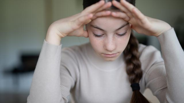 Junge Frau, die niedergeschlagen am Tisch sitzt
