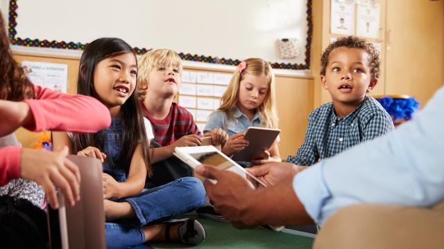 Grundschulklasse in der Runde sitzend mit Laptop