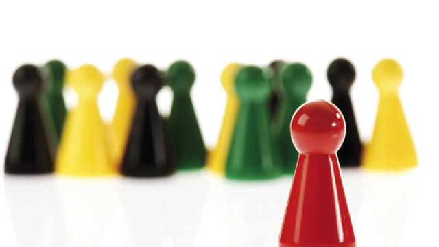 Einzelne rote Spielfigur vor andersfarbiger Gruppe