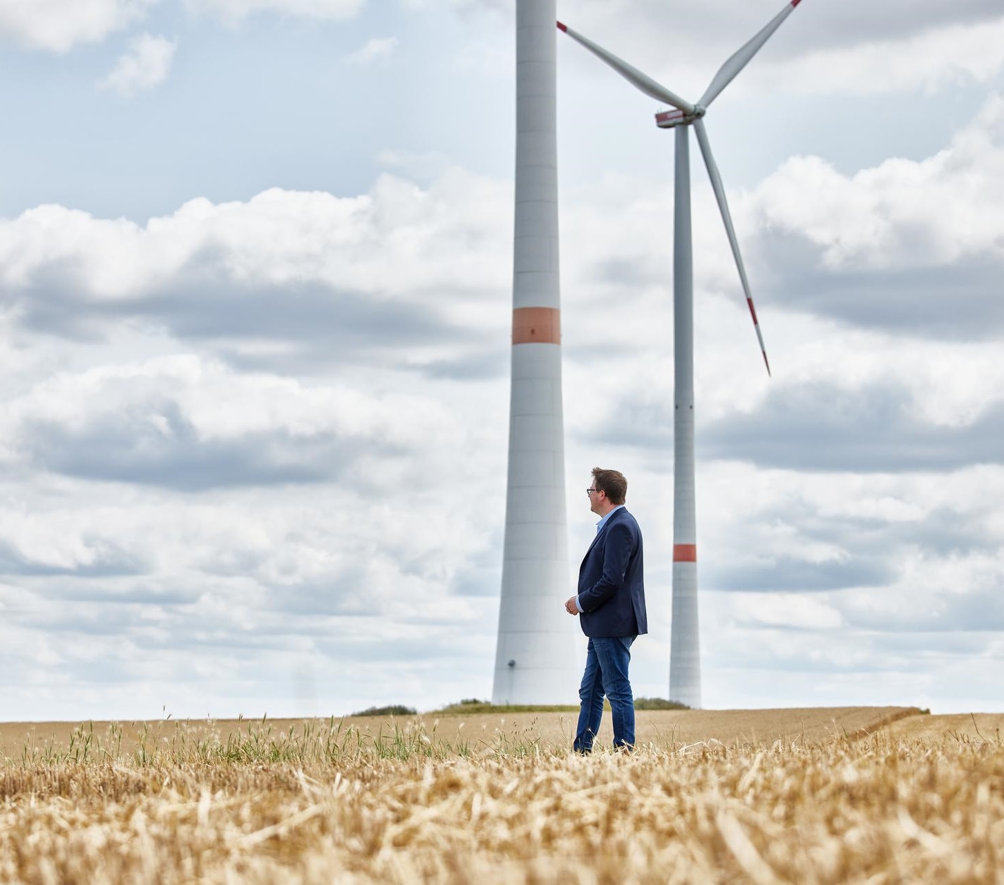 Oliver Koch vor zwei Windkraftanlagen.