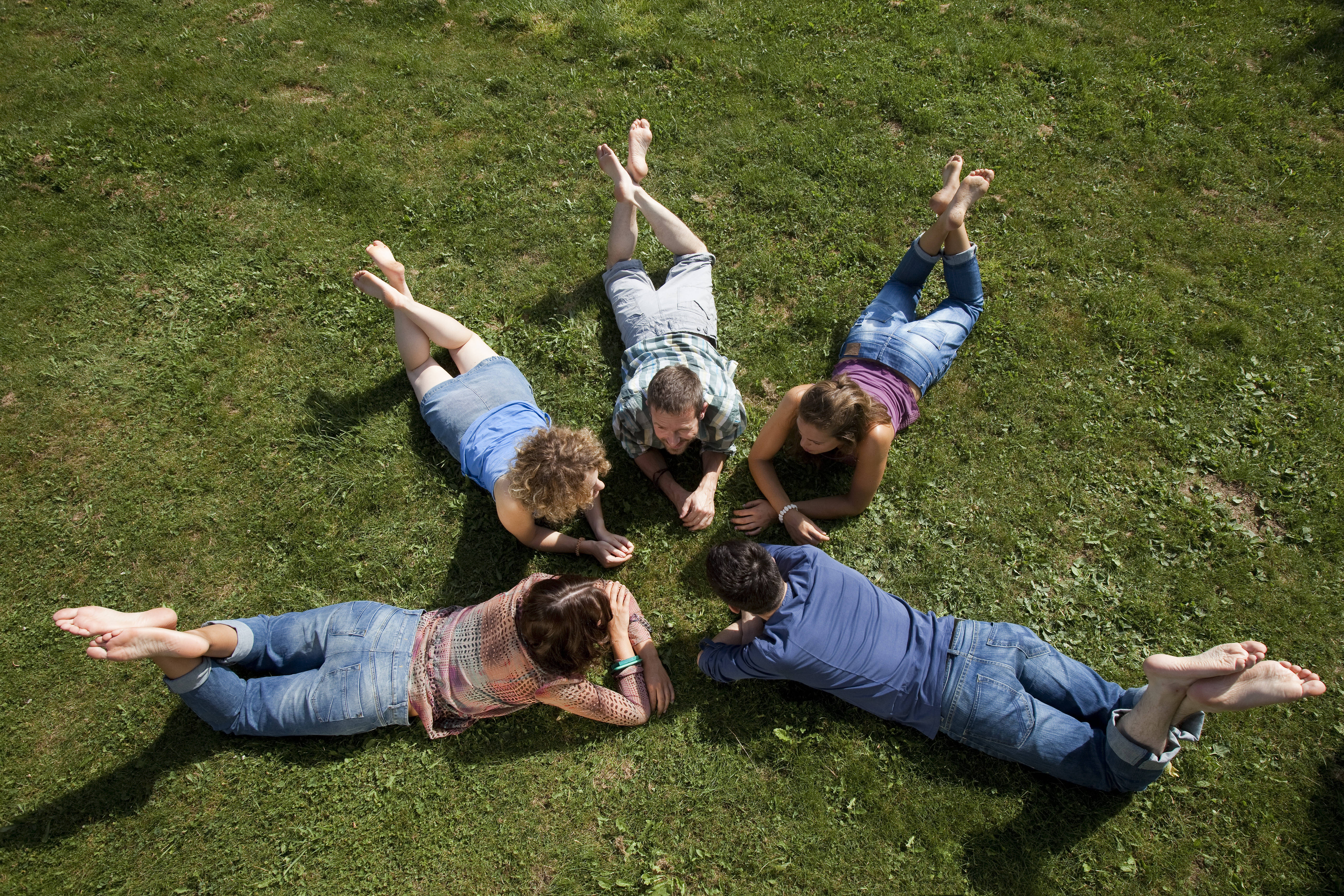 Gruppe von Menschen liegt im Kreis im Grünen