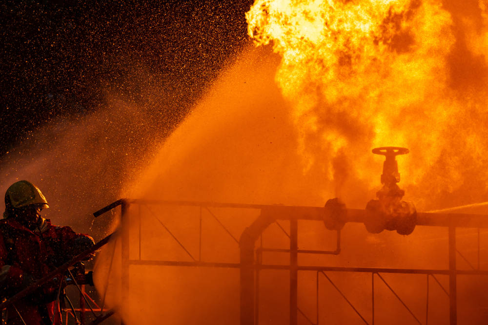 Firefighters using water fog spraying down fire from oil rig factory explosion.