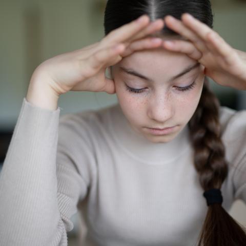 Junge Frau, die niedergeschlagen am Tisch sitzt
